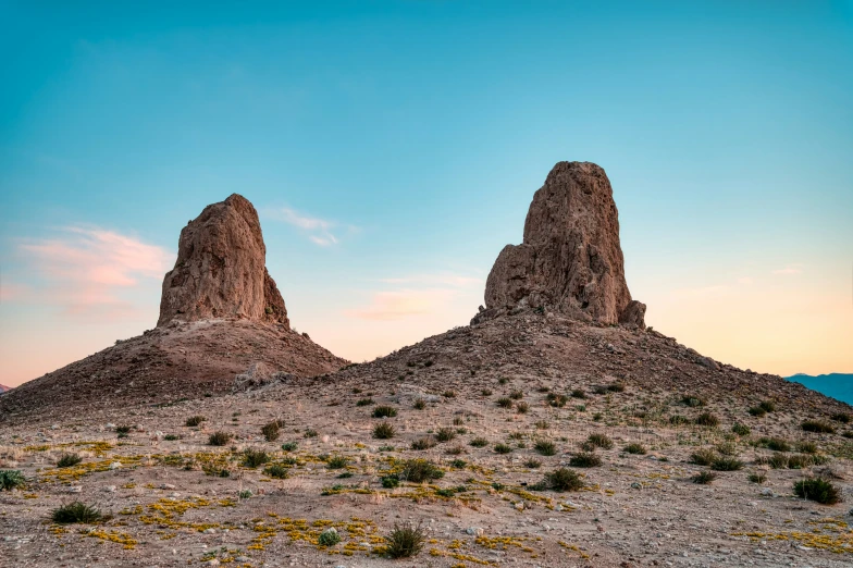 two tall rocks sitting on top of a hill in the desert