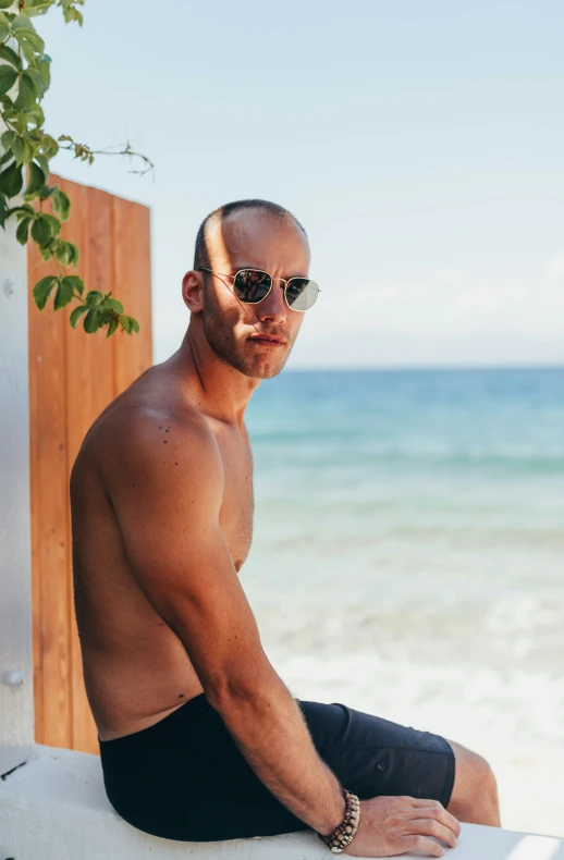 a man wearing sun glasses sitting on top of a white towel