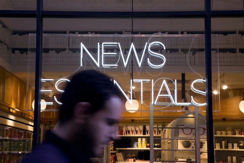 a man standing in front of a news advertit window