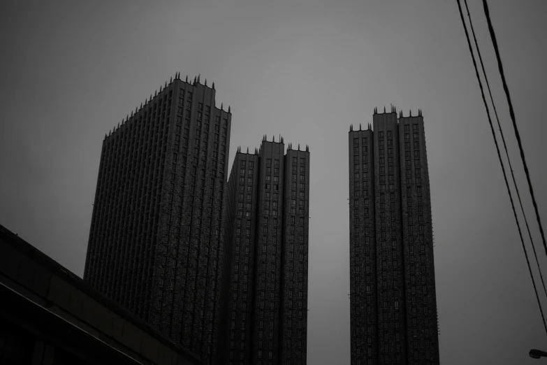 some tall buildings with many windows against a grey sky