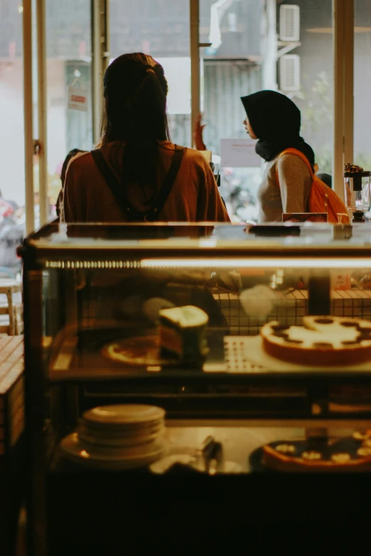 two people sitting in a restaurant looking into a window