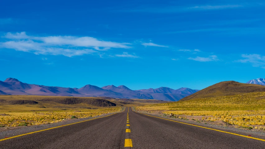 the long and wide road leading towards mountains