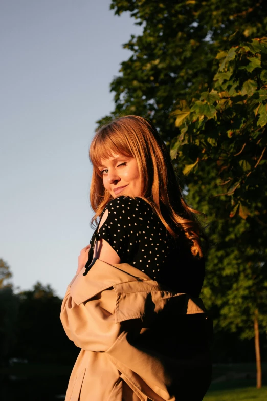 a woman with long hair wearing a tan trench