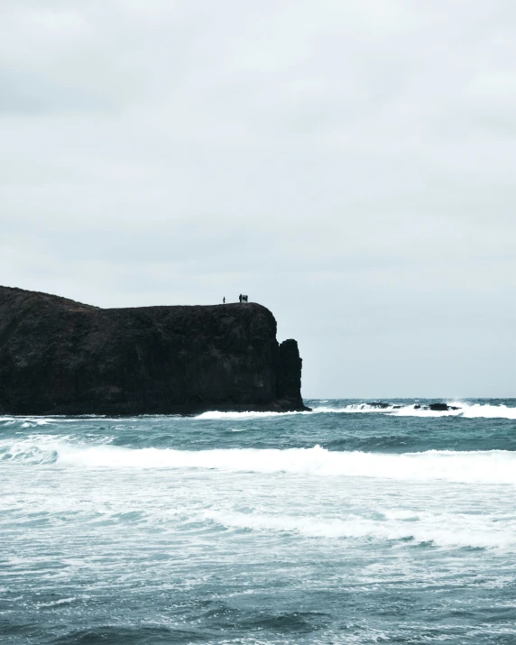 two people walk along the ocean shore