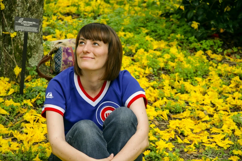 a woman sitting on the ground in front of flowers