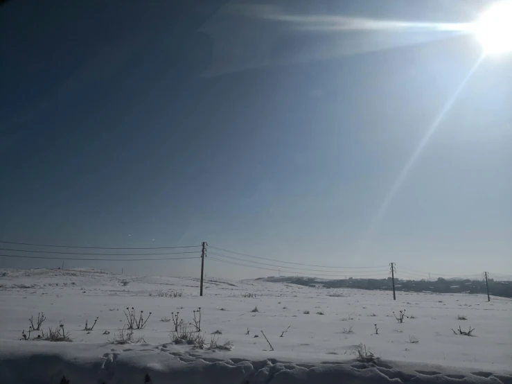 a view of a snow covered field with a line of power poles