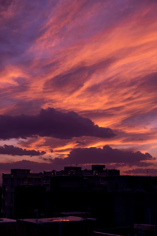 purple and orange clouds and buildings against a dark blue sky