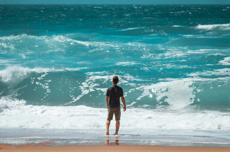 a man standing in the surf of the ocean