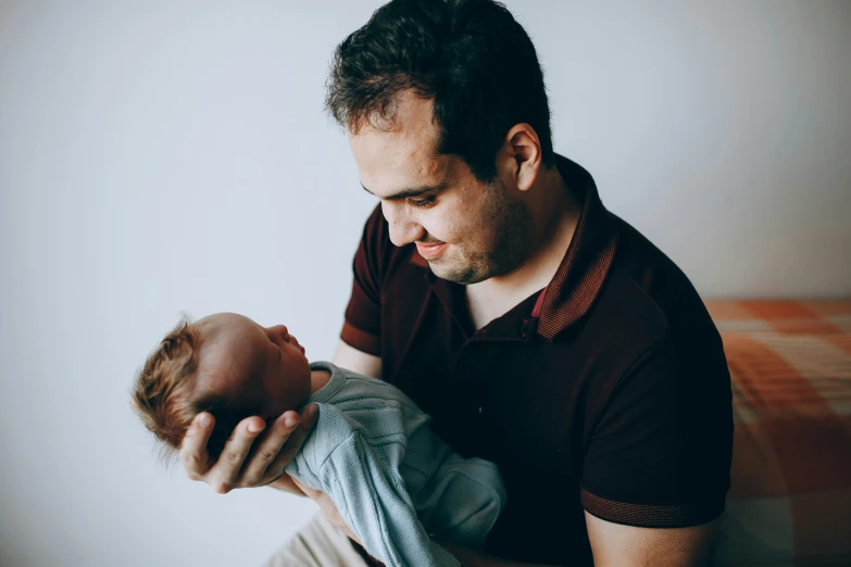 man holds his baby up to his chest