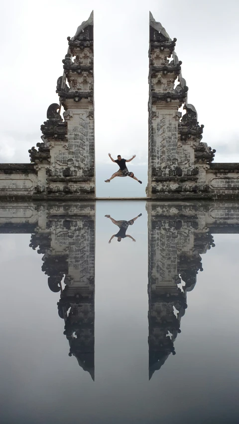 the silhouette of a person jumping in front of a gated entrance