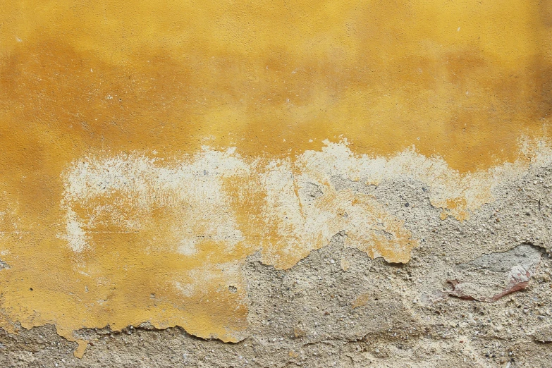 a yellow painted stucco wall with lots of dirt