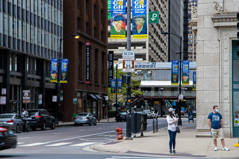 people are standing at an intersection and waiting for the traffic to change