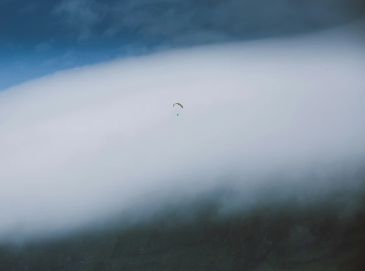 two people parachuting in the sky from behind some clouds