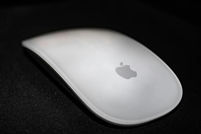 a wireless mouse with an apple logo sits on a table