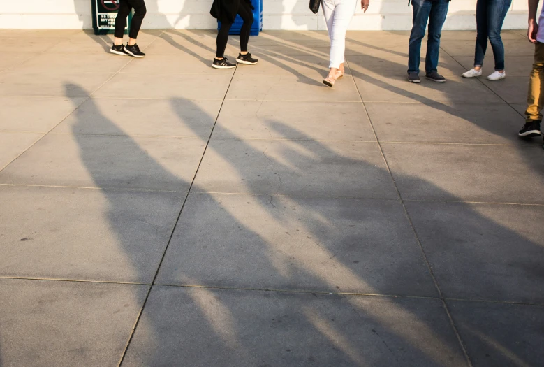 people casting a long shadow on a concrete walkway