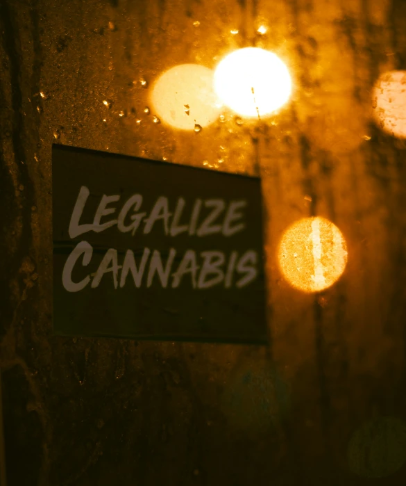 a sign that says legalize cannabis and lights in the background