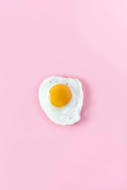 an egg is sitting on top of a pink surface