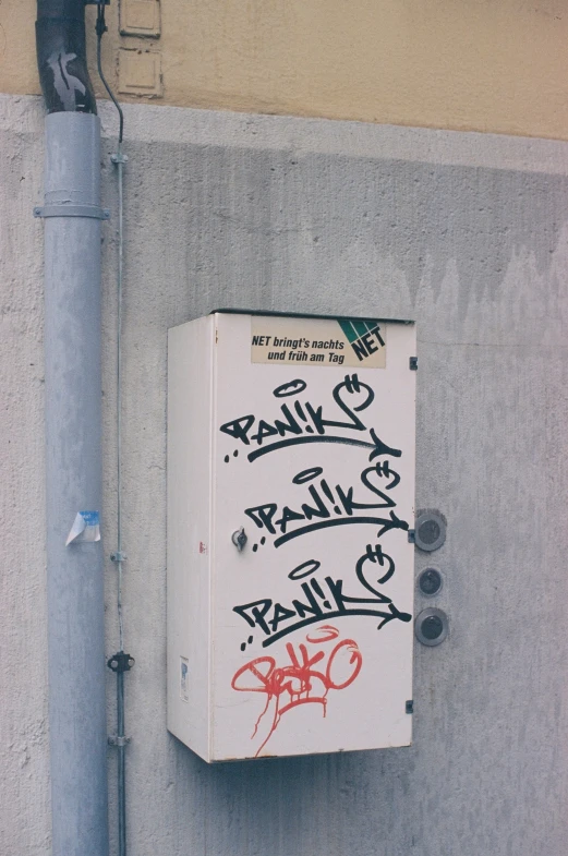 a small refrigerator is covered in graffiti next to a pole