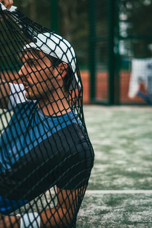 a tennis player rests in a net on the court