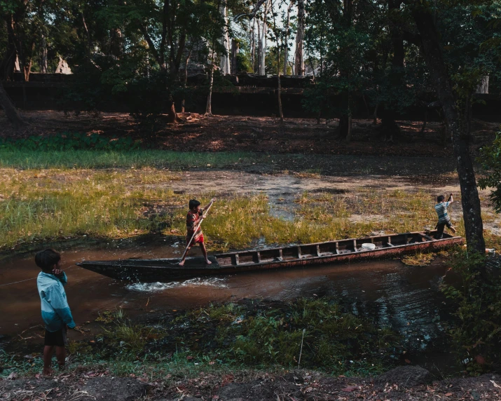 two s on a canoe in the mud by water