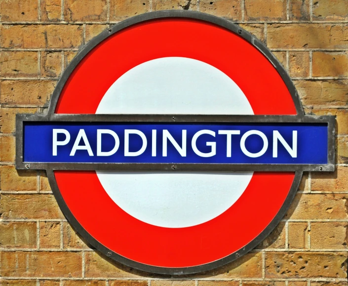 the sign for paddington is on a brick wall