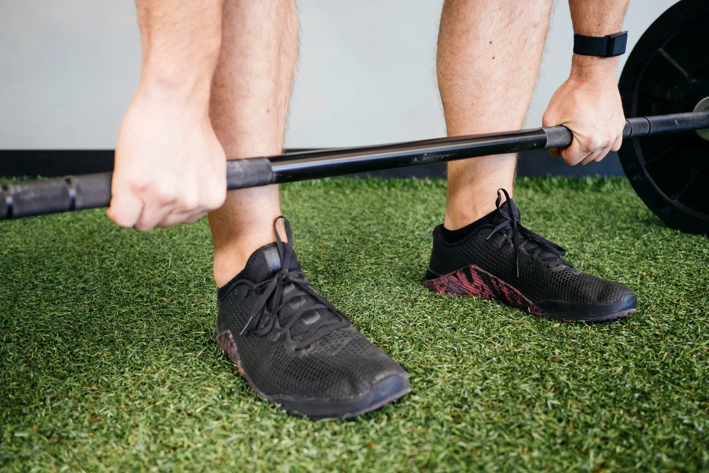 the legs and upper limb of a man holding a barbell