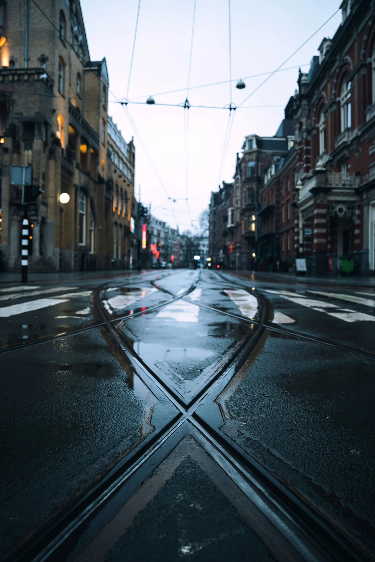 a rain soaked street with a double crosswalk in the middle