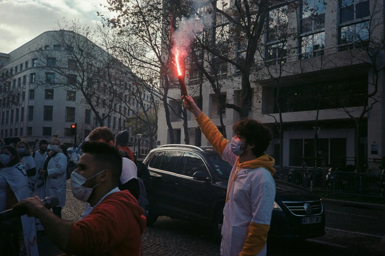 people wearing face masks holding onto sparklers near cars on a busy city street