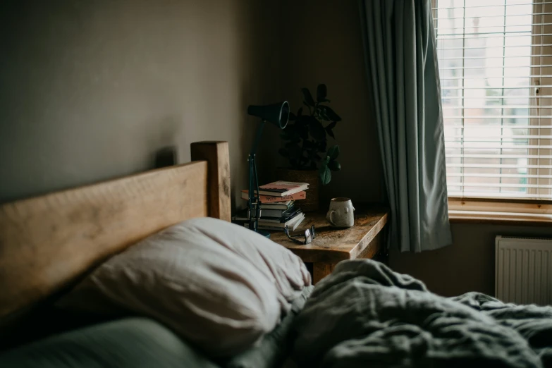 a bed sitting next to a window covered with a gray comforter