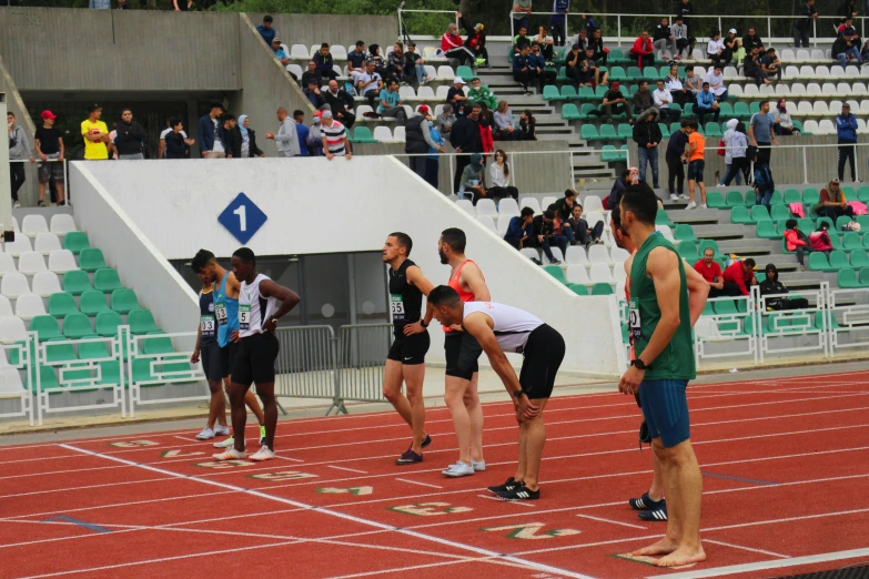 several people standing on a track, while people watch