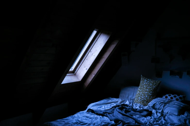 a bed sits under a window in the dark