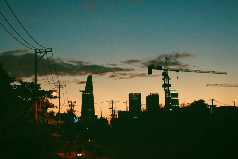 the city is silhouetted by its own cranes at dusk