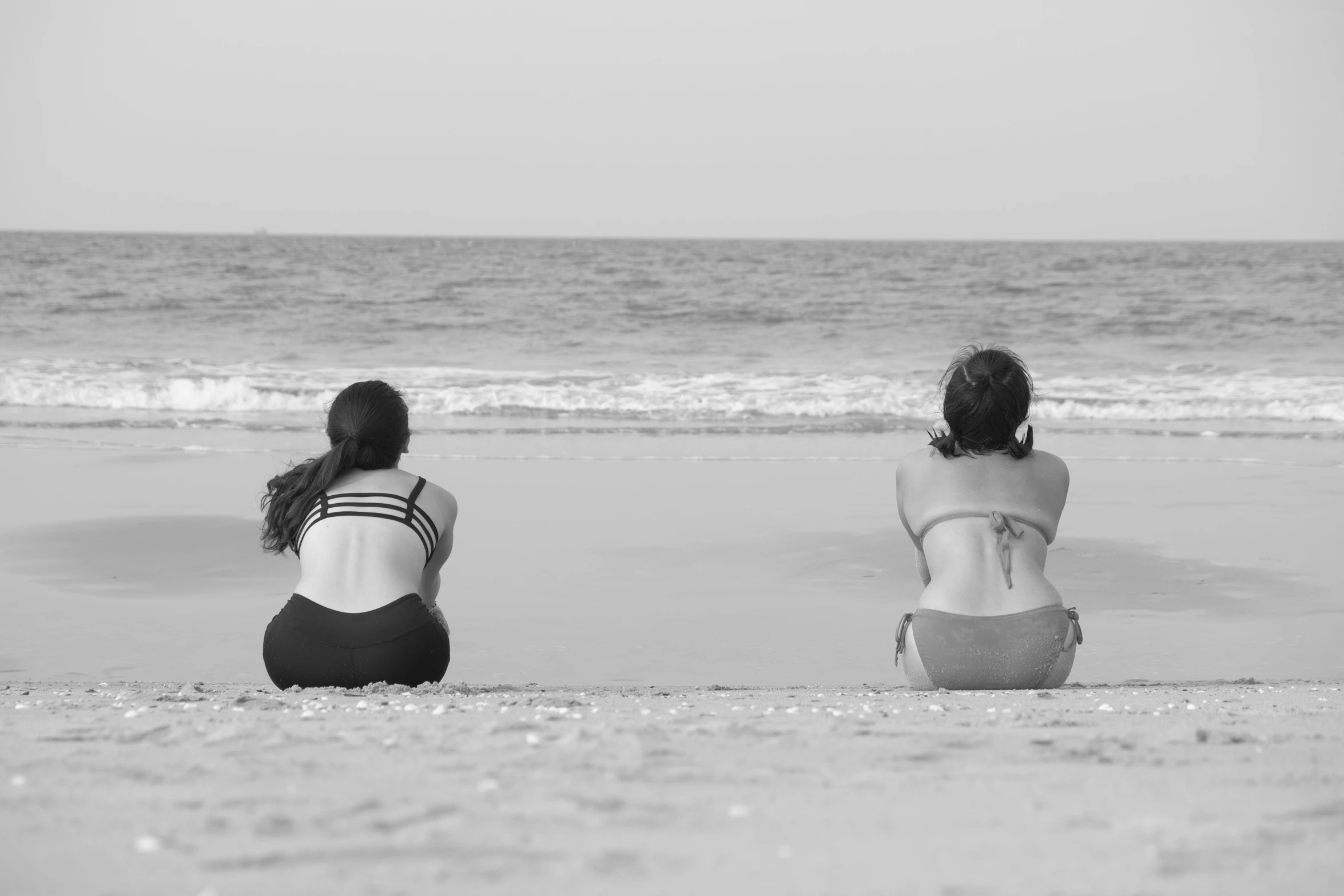 a couple of people sitting next to each other on top of a beach