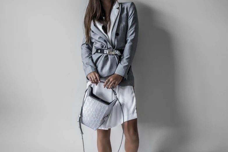 a woman is holding a white purse near a wall