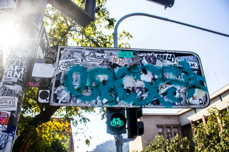 a green light pole with street sign and graffiti