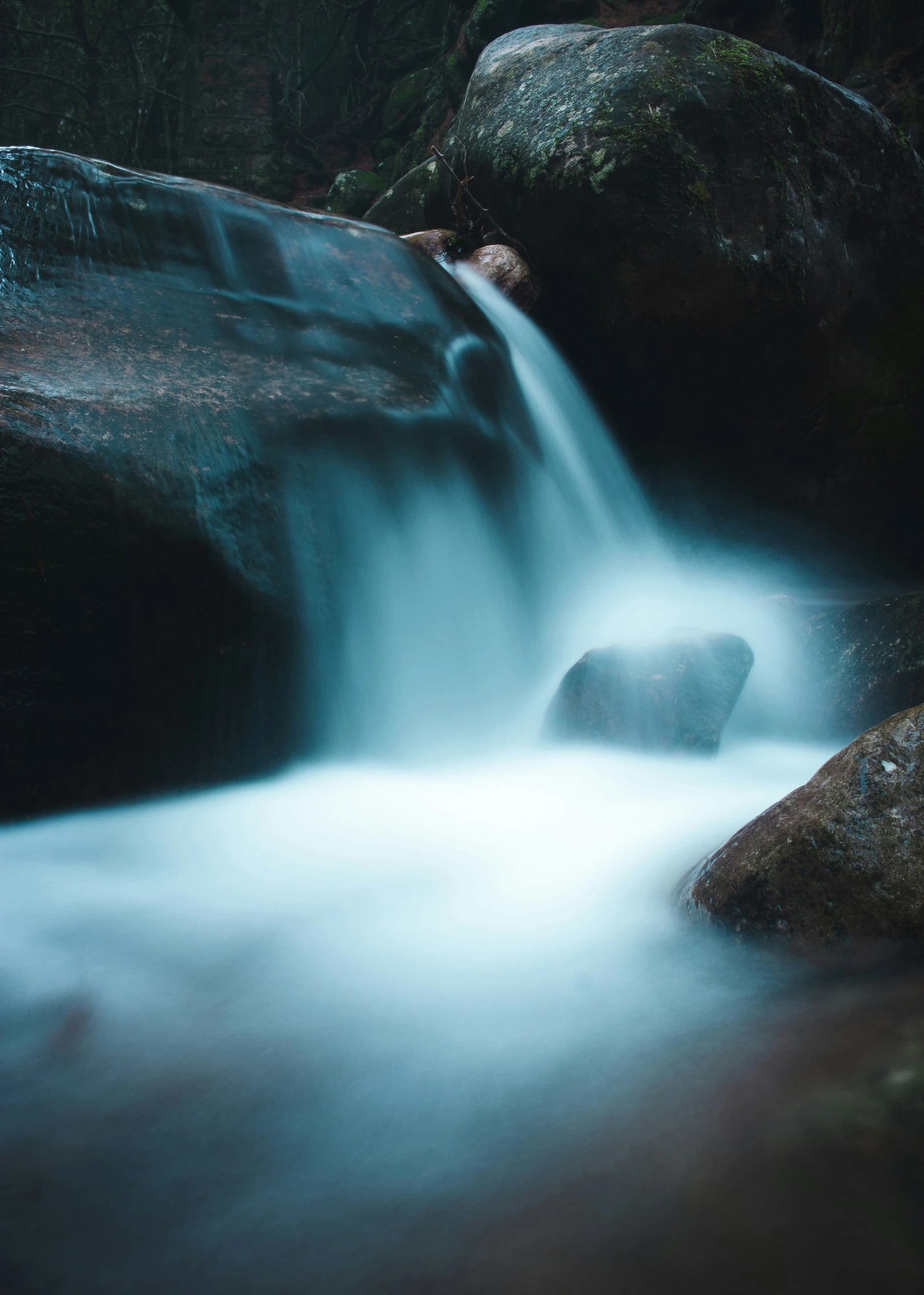 a very fast flowing waterfall next to some big rocks