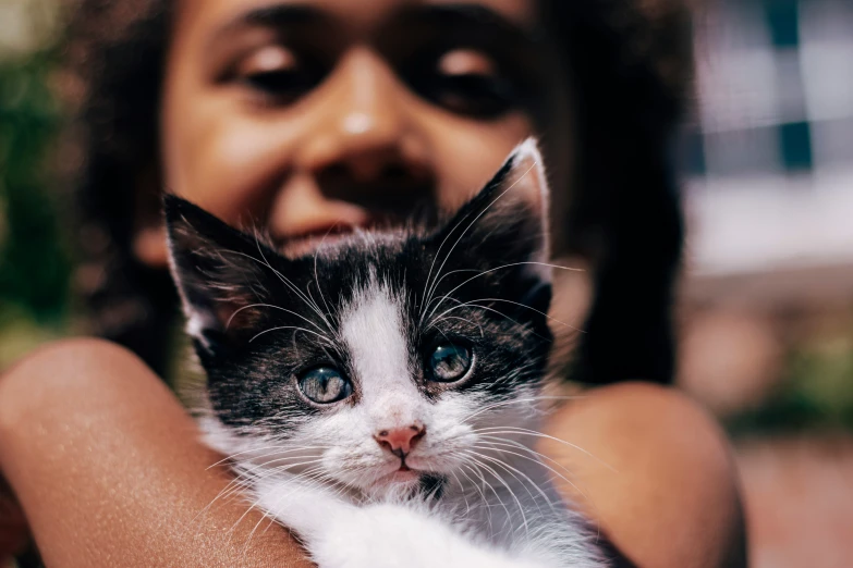 a black and white cat is being held in the arms of a woman