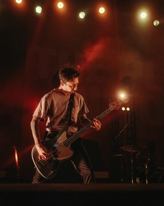 a young man holding an electric guitar under several lights
