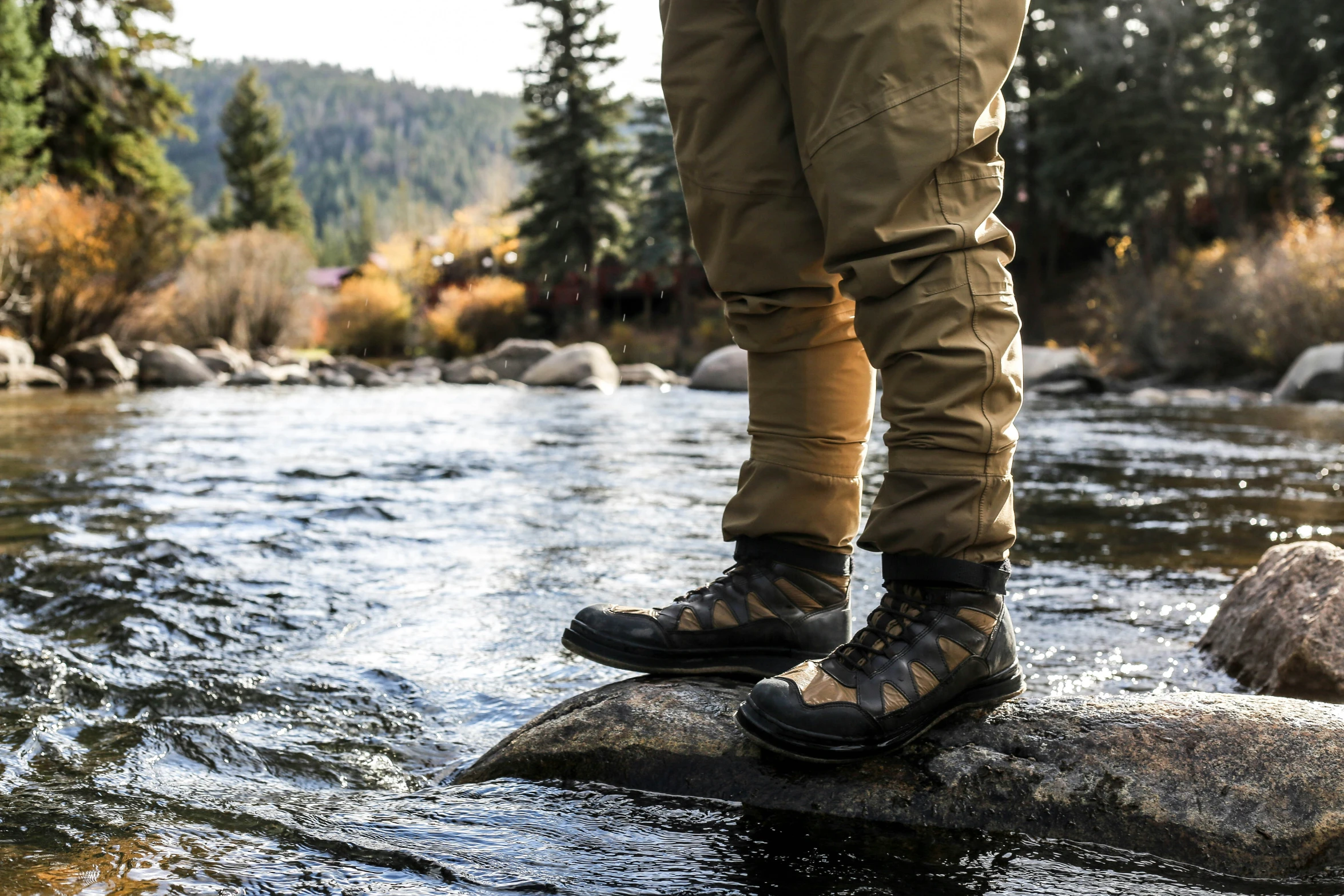 a person standing on a rock over a small stream