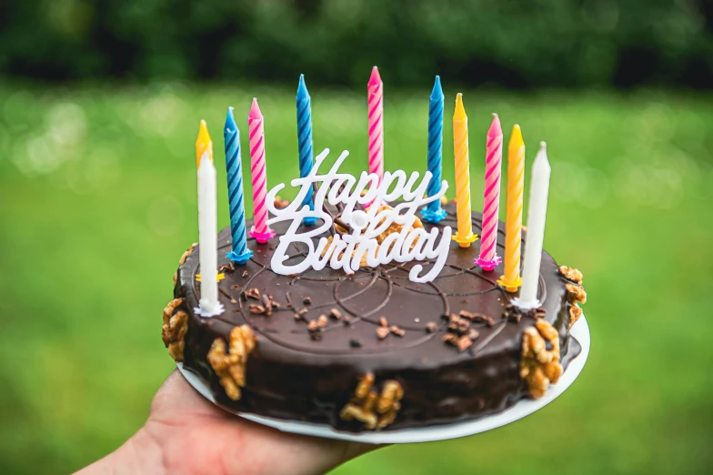 a hand holding a cake that has five lit candles on it