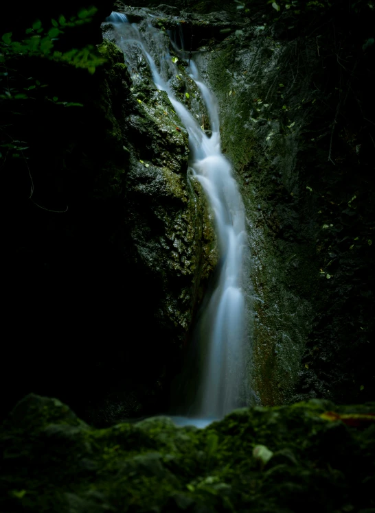 the small waterfall is located in the green rocky area