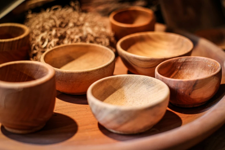 bowls and wooden spoons are arranged on a wood platter