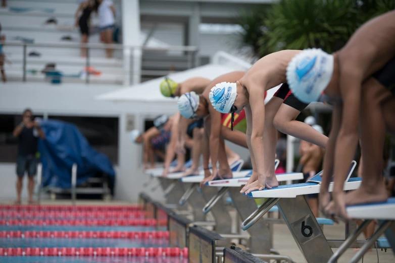 several swimmers on their knees near the starting blocks