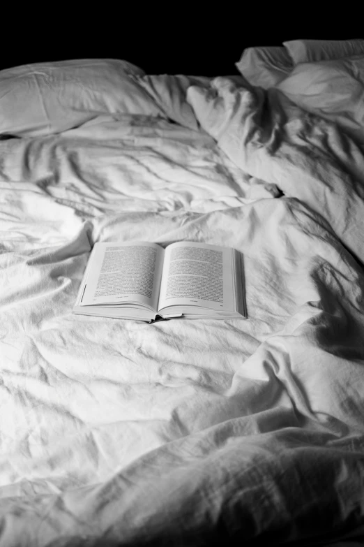 an open book sitting on top of a white bed sheet