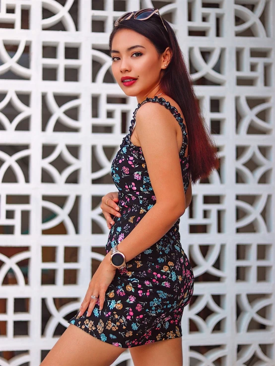 a woman wearing a floral dress in front of a white wall