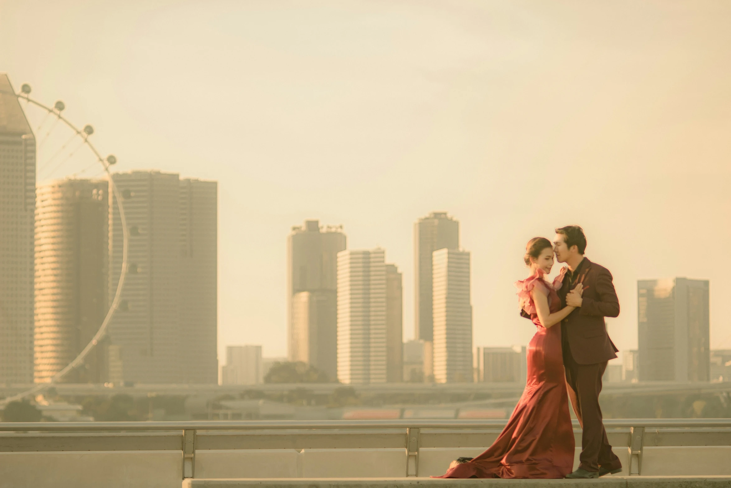 a man and woman are hugging while standing by a fence