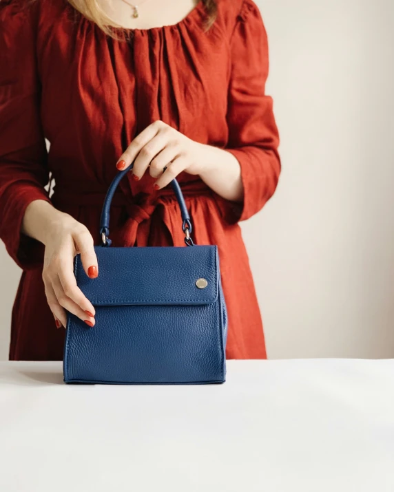 a woman in red holding onto a small blue purse