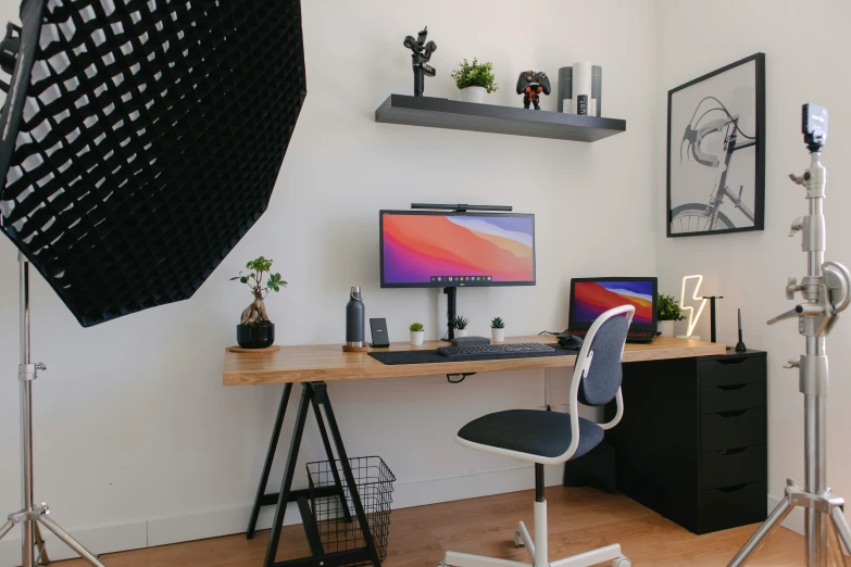 a desk with a monitor, keyboard and two other objects