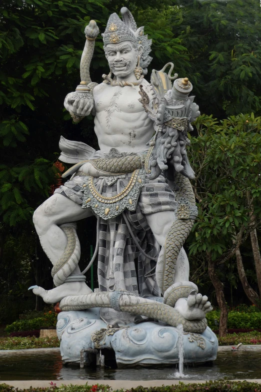 the statue of the mythical god is in front of trees