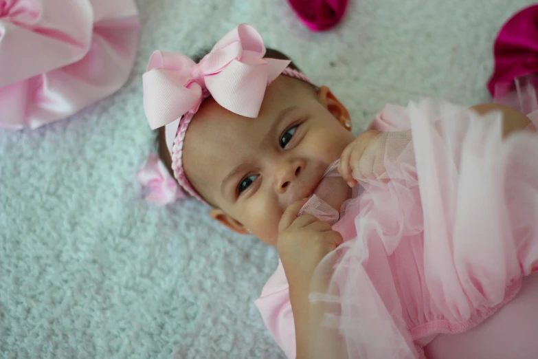 a baby girl wearing a pink dress and matching accessories